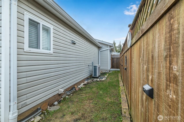 view of property exterior with fence, a lawn, and central air condition unit