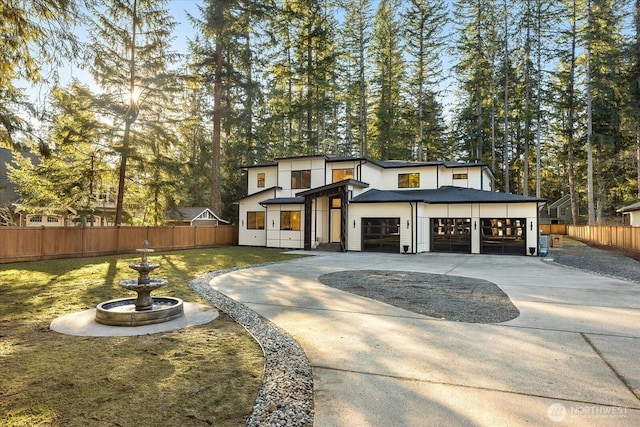 view of front of property featuring a garage, concrete driveway, fence, and a front lawn