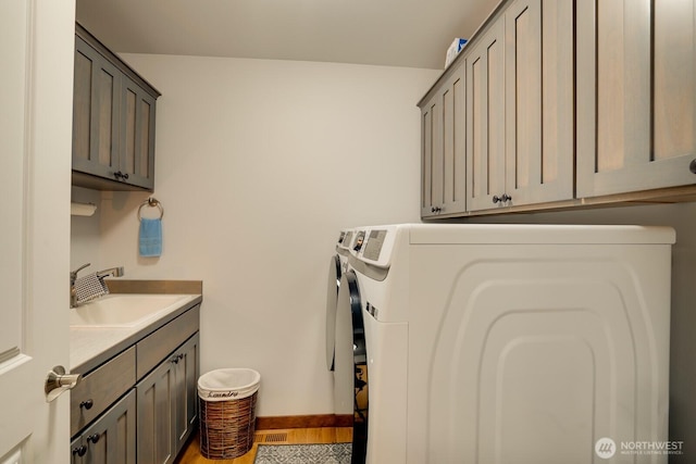 laundry area with sink, washer and clothes dryer, and cabinets