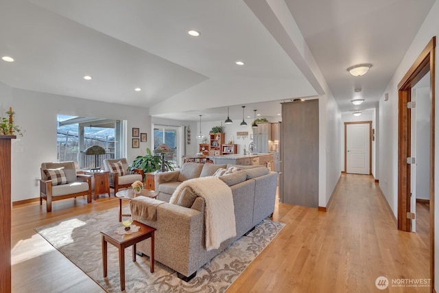 living room featuring sink, vaulted ceiling, and light hardwood / wood-style flooring