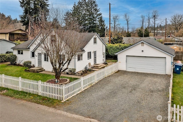 view of front of house with a shingled roof, a fenced front yard, an outdoor structure, and gravel driveway