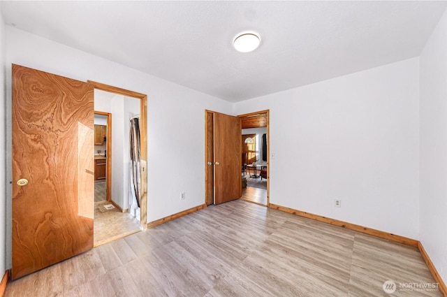 unfurnished bedroom with light wood-style flooring and baseboards