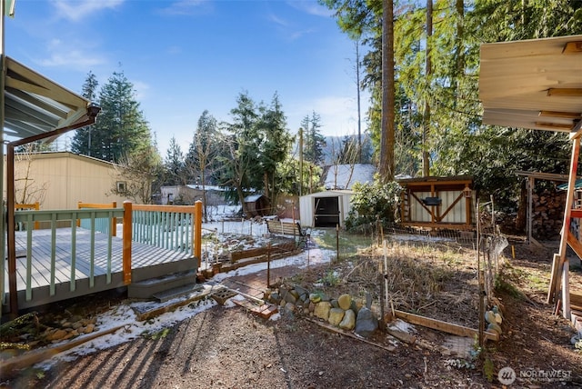 view of yard with a deck, a storage shed, an outdoor structure, and a vegetable garden