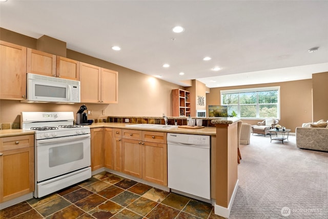 kitchen with sink, light brown cabinetry, white appliances, and kitchen peninsula