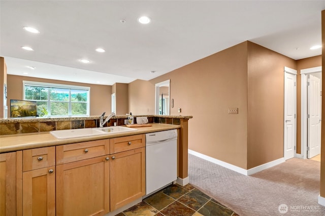 kitchen featuring dark colored carpet, dishwasher, sink, and light brown cabinets