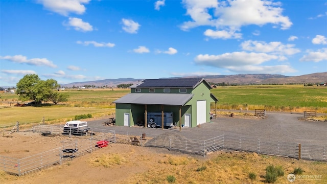 exterior space featuring an outbuilding, a rural view, a mountain view, and an outdoor structure