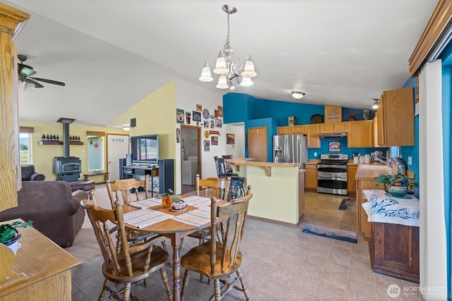 dining room with a wood stove, vaulted ceiling, and ceiling fan with notable chandelier