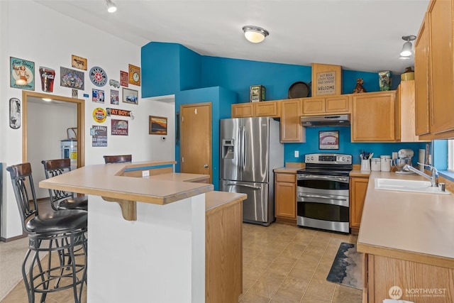 kitchen with a kitchen bar, stainless steel appliances, a sink, and light countertops