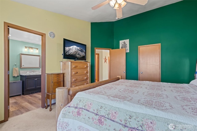 bedroom with connected bathroom, light colored carpet, a sink, a ceiling fan, and vaulted ceiling