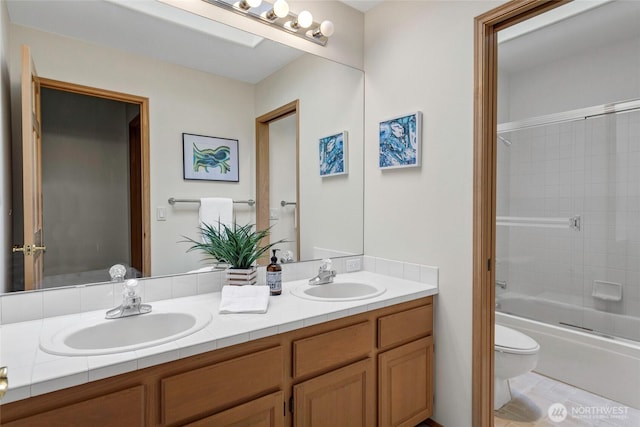 full bathroom featuring enclosed tub / shower combo, double vanity, a sink, and toilet