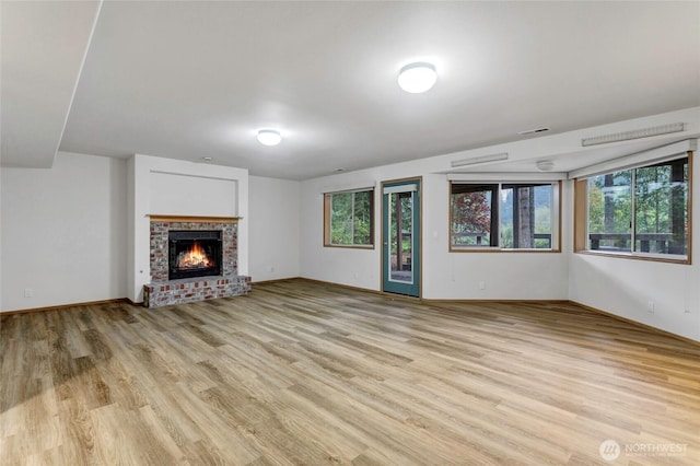 unfurnished living room featuring light wood-style floors, a fireplace, plenty of natural light, and visible vents