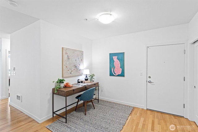 office space featuring light wood finished floors, baseboards, and visible vents