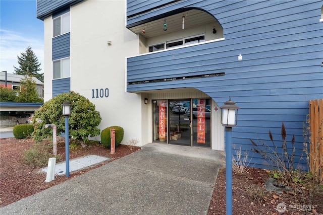 entrance to property with stucco siding and a balcony