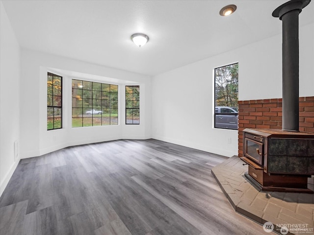 unfurnished living room featuring a wood stove and hardwood / wood-style floors