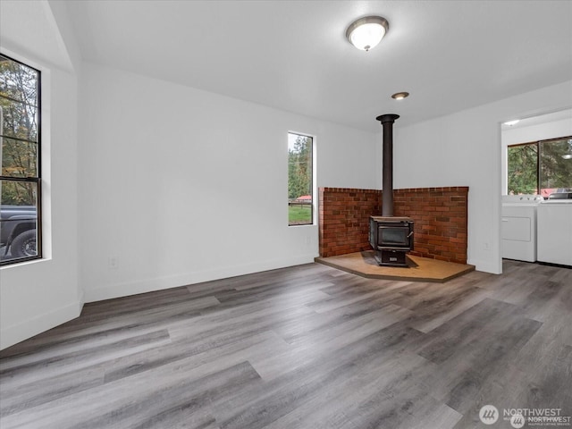 unfurnished living room featuring hardwood / wood-style floors, a wood stove, plenty of natural light, and separate washer and dryer