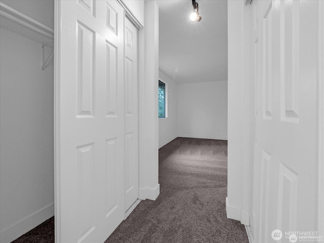 hall featuring rail lighting and dark colored carpet