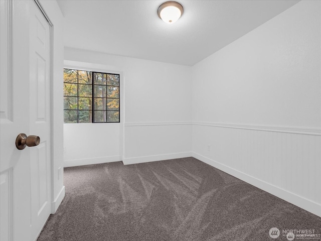 unfurnished room featuring dark carpet