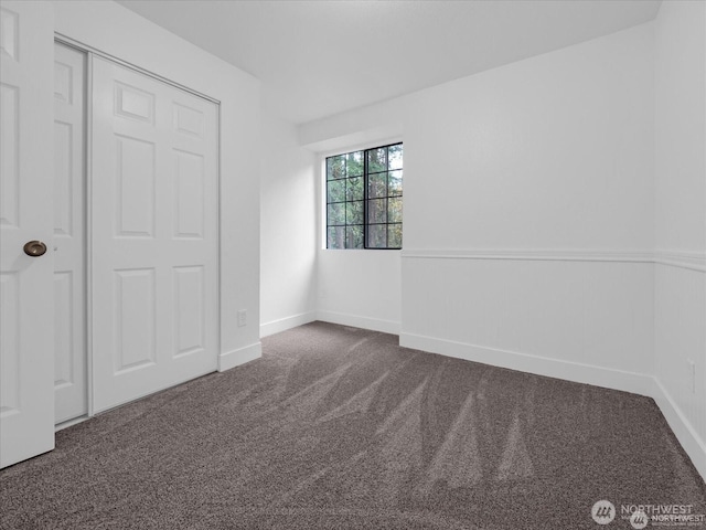 unfurnished bedroom with a closet and dark colored carpet