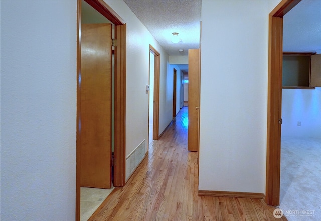 hall featuring light hardwood / wood-style floors and a textured ceiling