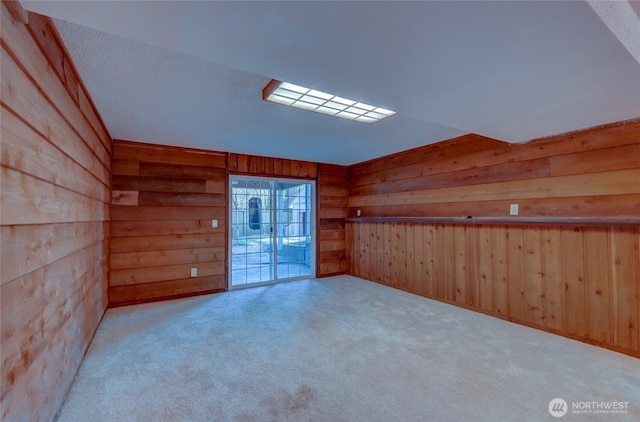 carpeted empty room featuring wood walls