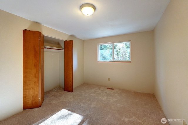 unfurnished bedroom featuring light colored carpet and a closet