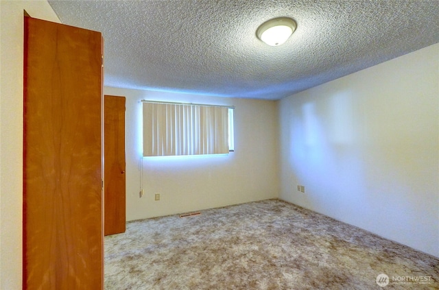 unfurnished room featuring light colored carpet and a textured ceiling