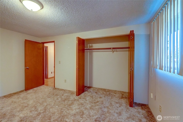 unfurnished bedroom featuring light carpet, a textured ceiling, and a closet