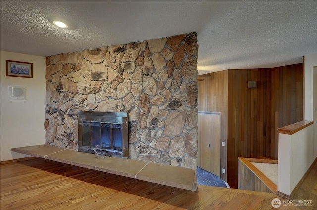 unfurnished living room featuring a fireplace, light hardwood / wood-style floors, and a textured ceiling