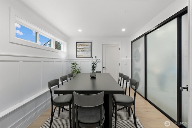 dining area featuring wainscoting, recessed lighting, light wood-style flooring, and a decorative wall