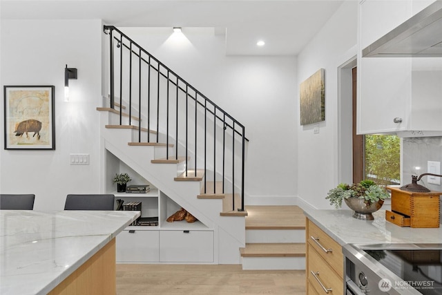 stairway with wood finished floors and recessed lighting