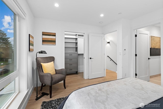 bedroom featuring baseboards, light wood finished floors, a walk in closet, and recessed lighting