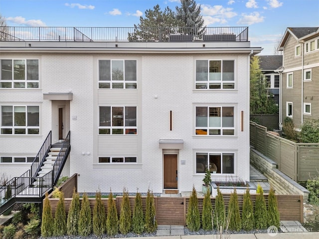 view of front of house featuring fence and brick siding