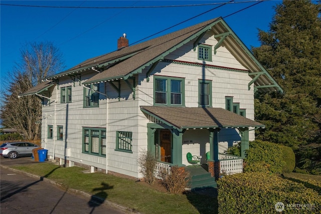 victorian-style house with a shingled roof, covered porch, and a chimney