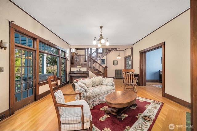 living room featuring radiator, a chandelier, stairway, baseboards, and wood finished floors