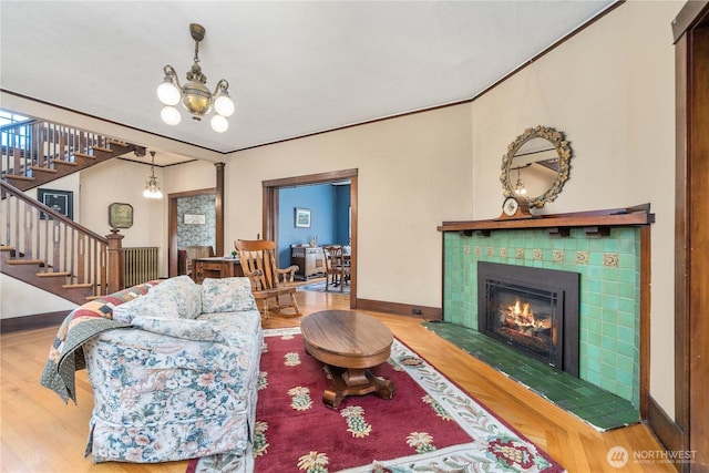 living area with a chandelier, wood finished floors, stairway, baseboards, and a tiled fireplace