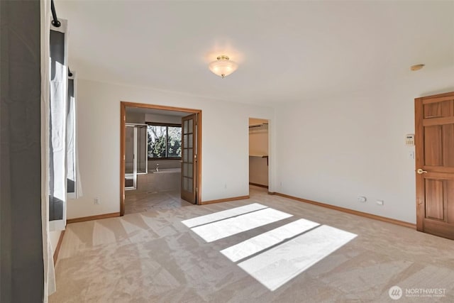 interior space with connected bathroom, a spacious closet, and light carpet