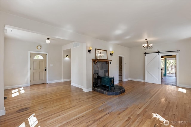 205 S Division, Cashmere, WA 98815 - unfurnished living room featuring a wood stove, light wood-type flooring, a chandelier, baseboards, and a barn door