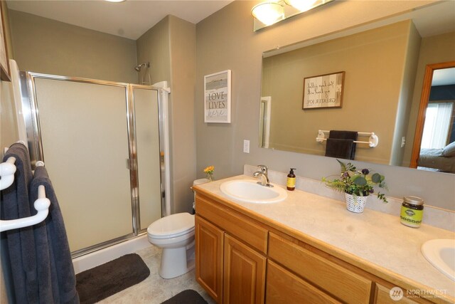 full bath with double vanity, a stall shower, toilet, and a sink