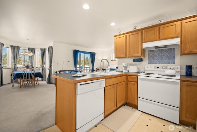 kitchen featuring decorative light fixtures, sink, kitchen peninsula, a healthy amount of sunlight, and white appliances