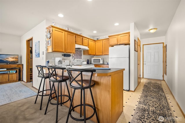 kitchen with a kitchen breakfast bar, a kitchen island, and white appliances