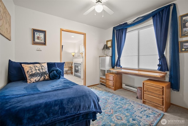 carpeted bedroom with ensuite bathroom, a baseboard heating unit, and ceiling fan