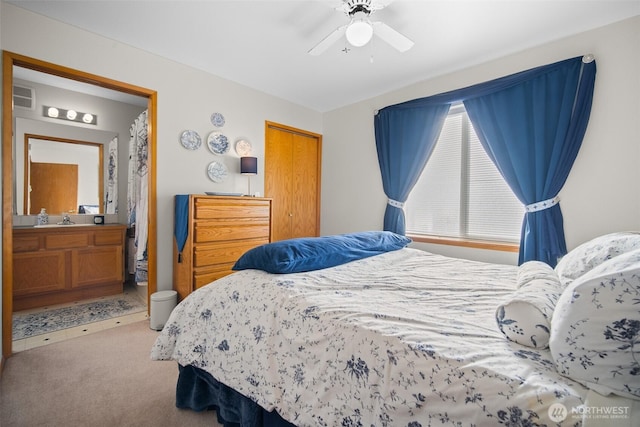 carpeted bedroom with ceiling fan and ensuite bath