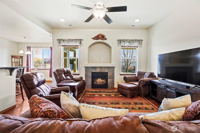 living room featuring hardwood / wood-style flooring, ceiling fan, and a tiled fireplace