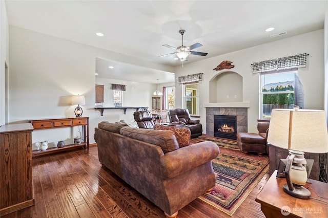 living room featuring ceiling fan, dark hardwood / wood-style floors, and a fireplace