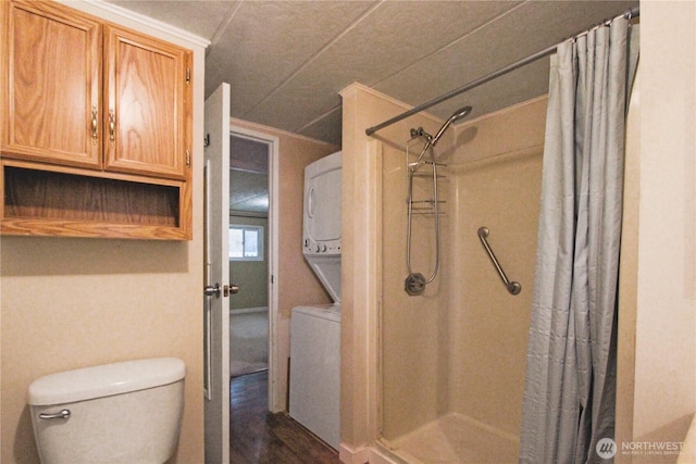 bathroom with a shower with curtain, stacked washer and clothes dryer, and toilet