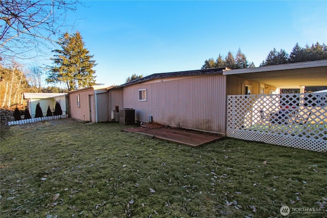 rear view of property featuring a yard and central air condition unit