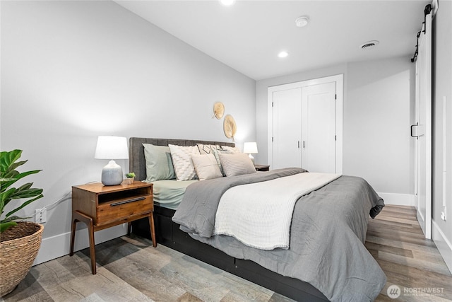 bedroom with light hardwood / wood-style floors, a closet, and a barn door