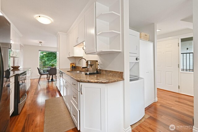 220 SW 200th St Unit 186, Normandy Park, WA 98166 - kitchen featuring stove, stacked washer and clothes dryer, open shelves, and white cabinetry