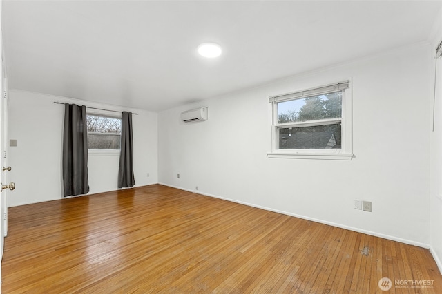 unfurnished room featuring light wood-type flooring and a wall unit AC