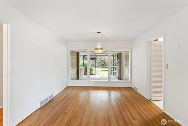 unfurnished dining area featuring light hardwood / wood-style flooring and a notable chandelier